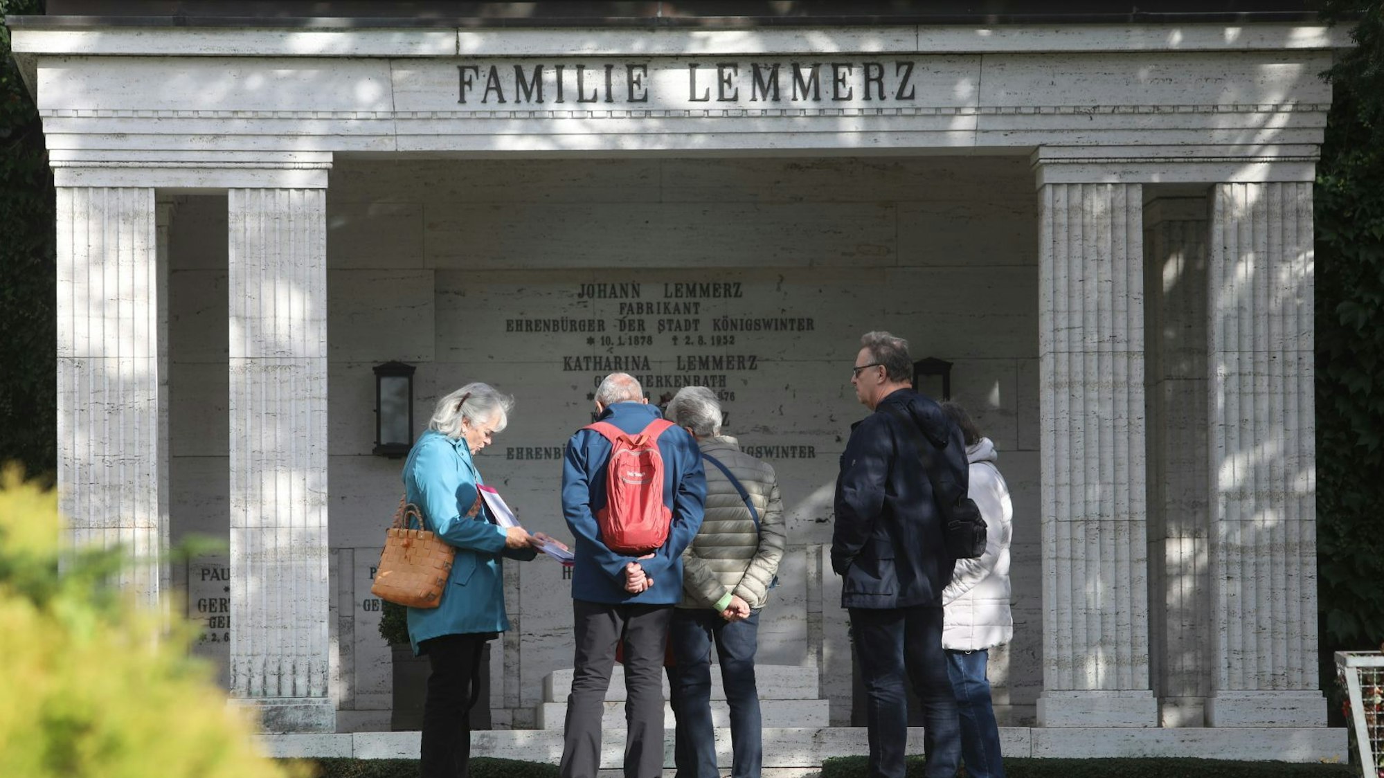 Eine Gruppe von Menschen stehen vor dem großen Familiengrab der Familie Lemmerz.