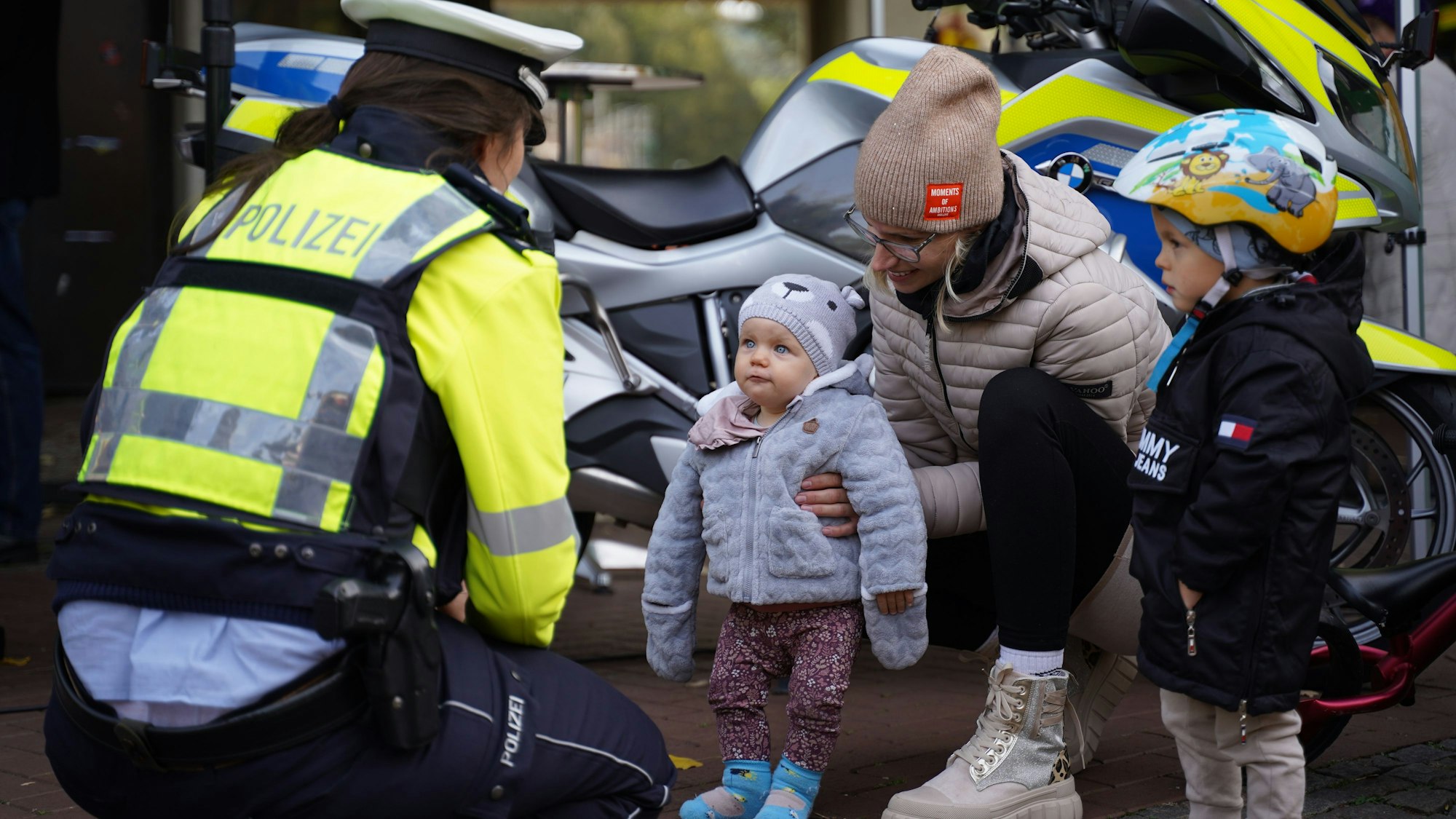 Bürgernähe, aber schon früh: Eine Polizistin spricht beim „Coffee with a cop“ in Leichlingen mit einer Frau und ihren beiden kleinen Kindern.