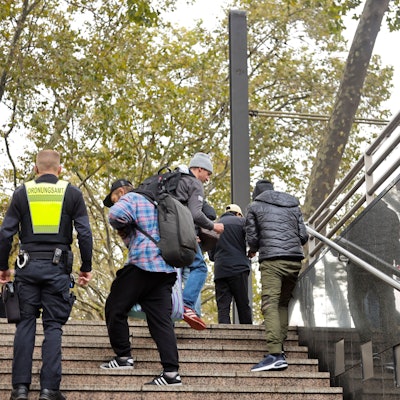 Das Bild zeigt einen Mitarbeiter der Stadt, der auf einer Treppe am Neumarkt Menschen kontrolliert.