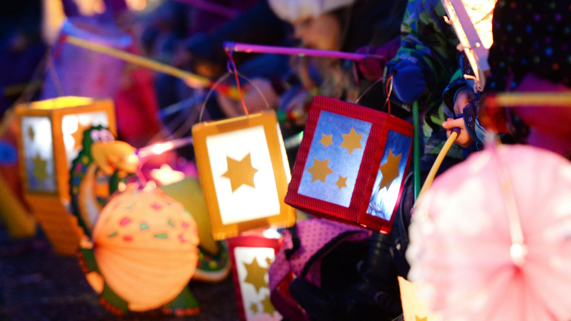 Kinder halten ihren leuchtenden Laternen in die Höhe.