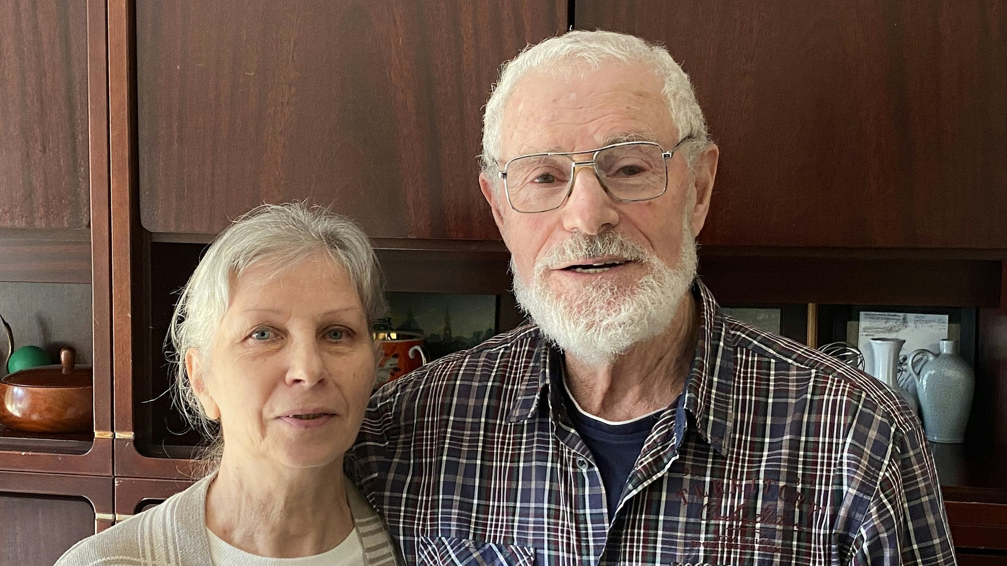 Ein Ehepaar steht vor einer Schrankwand.