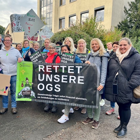 Mitarbeiterinnen, Eltern und Kinder mit Plakaten für eine bessere finanzielle OGS-Ausstattung.