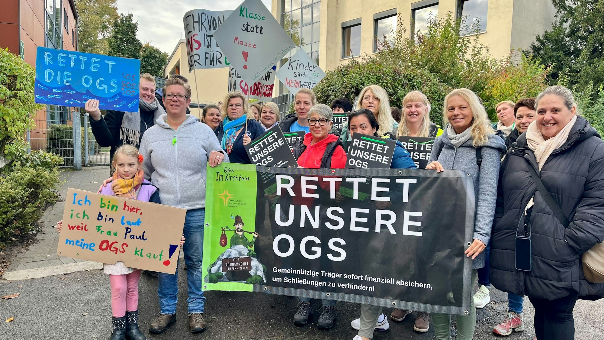 Mitarbeiterinnen, Eltern und Kinder mit Plakaten für eine bessere finanzielle OGS-Ausstattung.