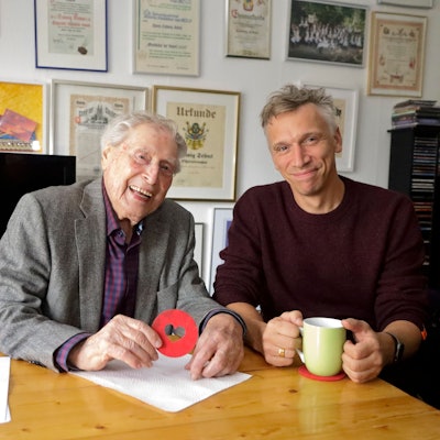 Ludwig Sebus und Basti Campmann sitzen an einem Tisch, im Hintergrund sind Orden und Urkunden zu sehen.