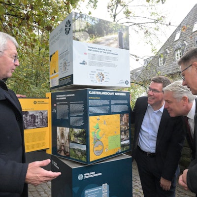 Unter anderem Landrat Stephan Santelmann und Bürgermeister Robert Lennerts schauen auf die Infotafel des Wanderweges.