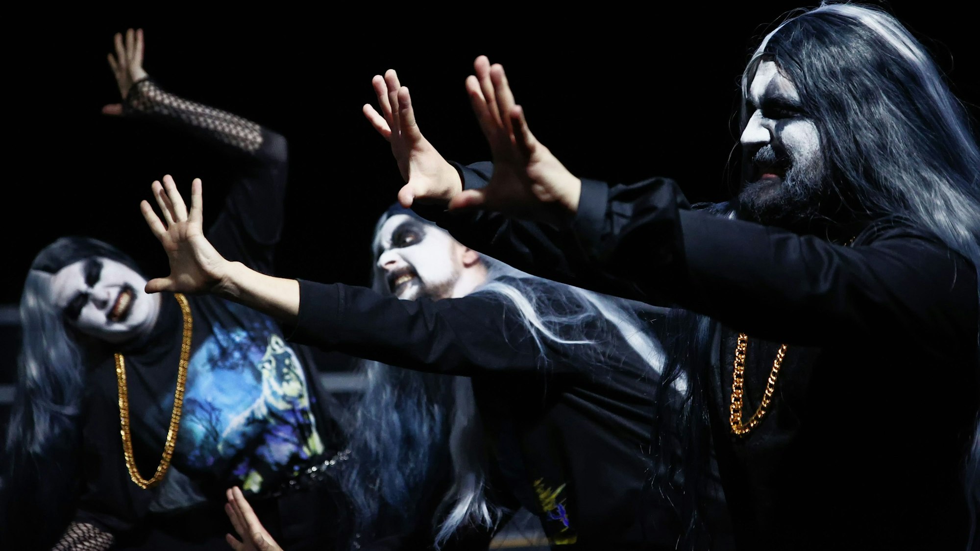Zu sehen sind Schauspieler im Gothic-Look: Weiß-schwarze Schminke im Gesicht, schwarze Kleidung und lange dunkle Haare. Sie strecken die Hände aus und machen Fratzen.