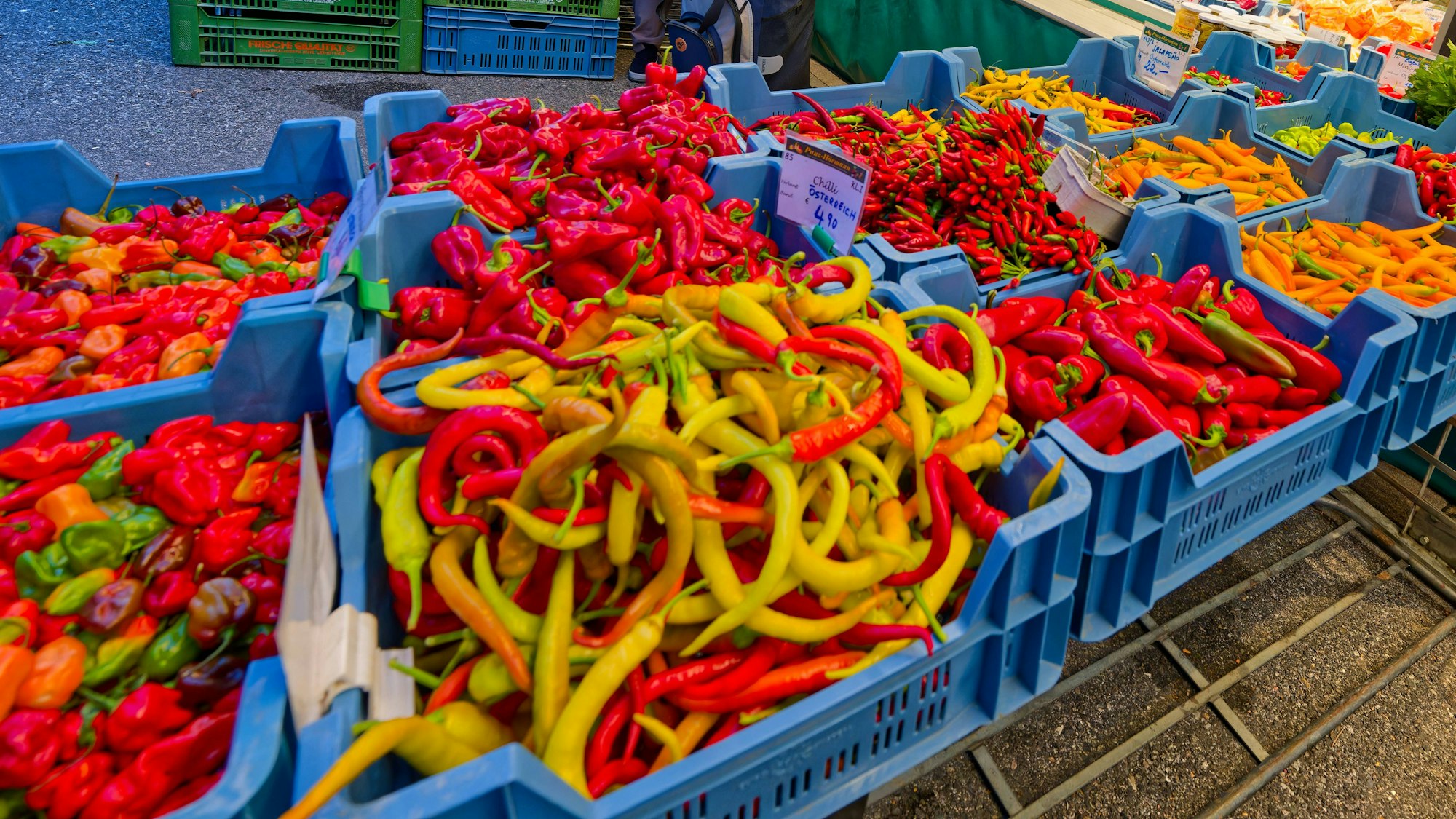 Auf einem Markt ist buntes Gemüse zu sehen, vor allem verschiedene Sorten von Paprika.
