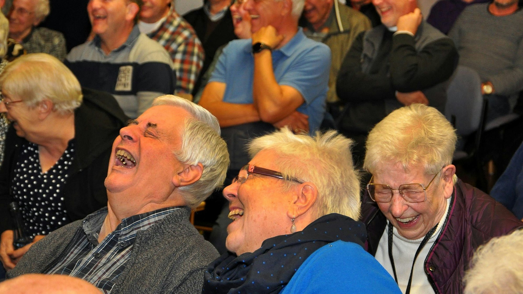 Das Bild zeigt lachende Besucher im voll besetzten Kaller Pfarrheim.