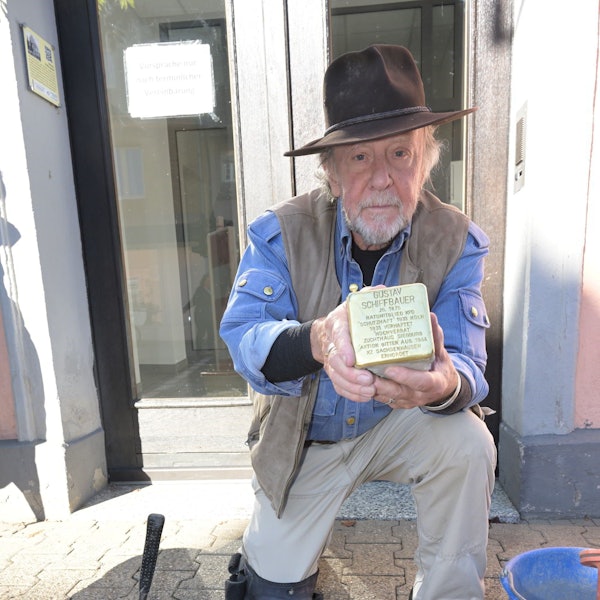 Das Foto zeigt Günter Demnig mit dem Stolperstein für Gunter Demnig.