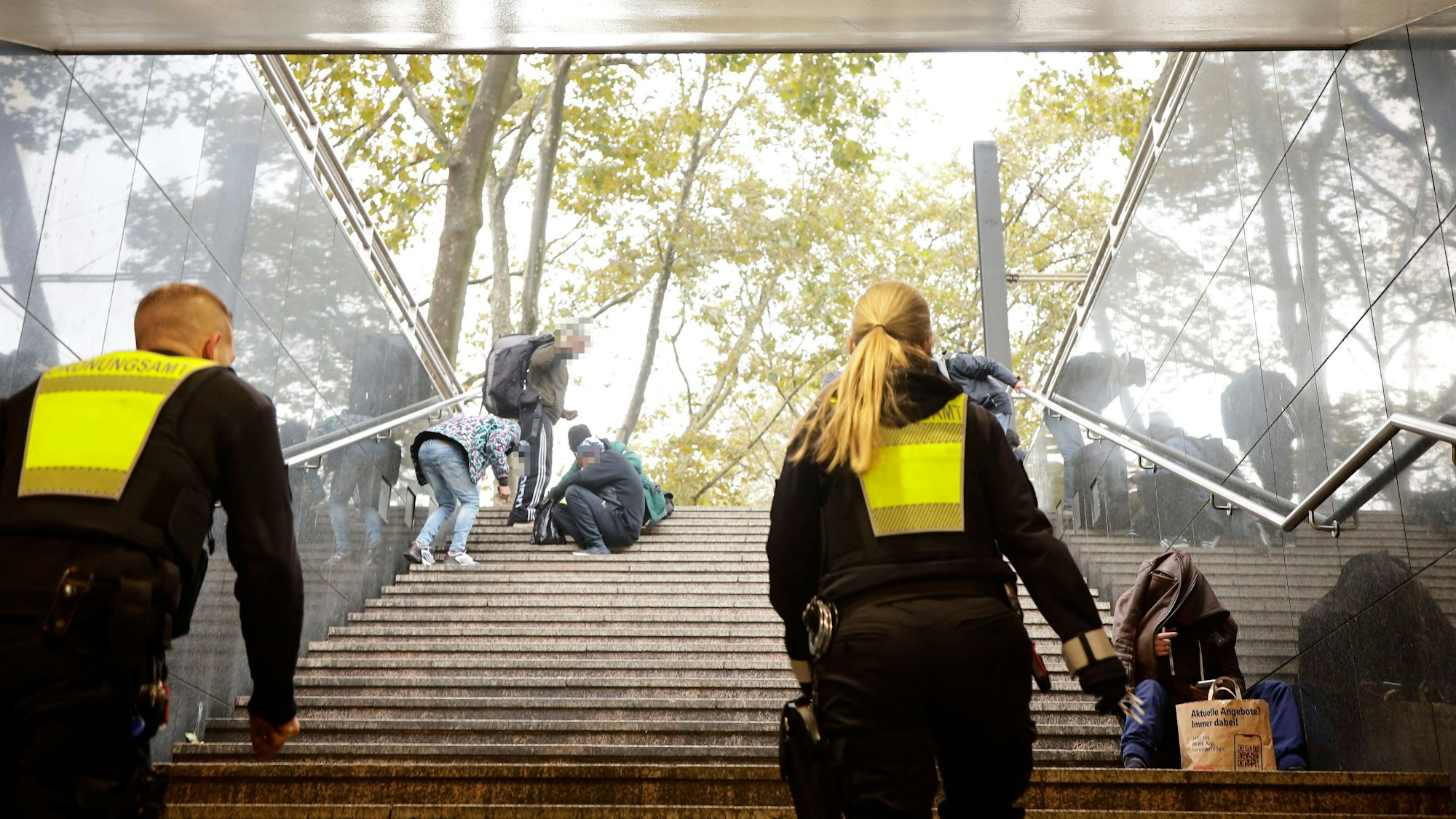 Zwei Mitarbeitende des Ordnungsamtes gehen die Treppen an der Neumarkt-Unterführung hoch, dort sitzen Drogenabhängige.