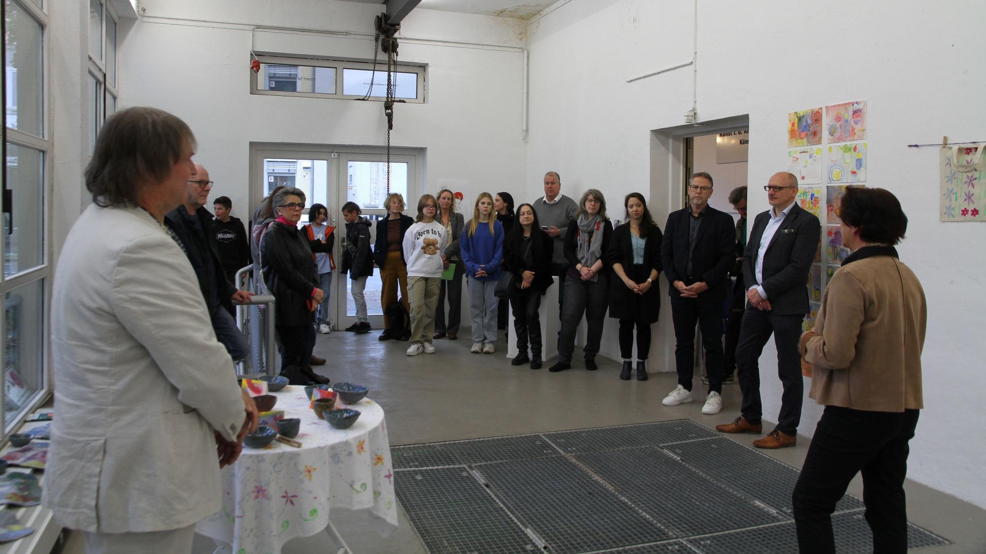 Eine Gruppe von Menschen in einem hellen Ausstellungsraum mit Bildern und Plastiken
