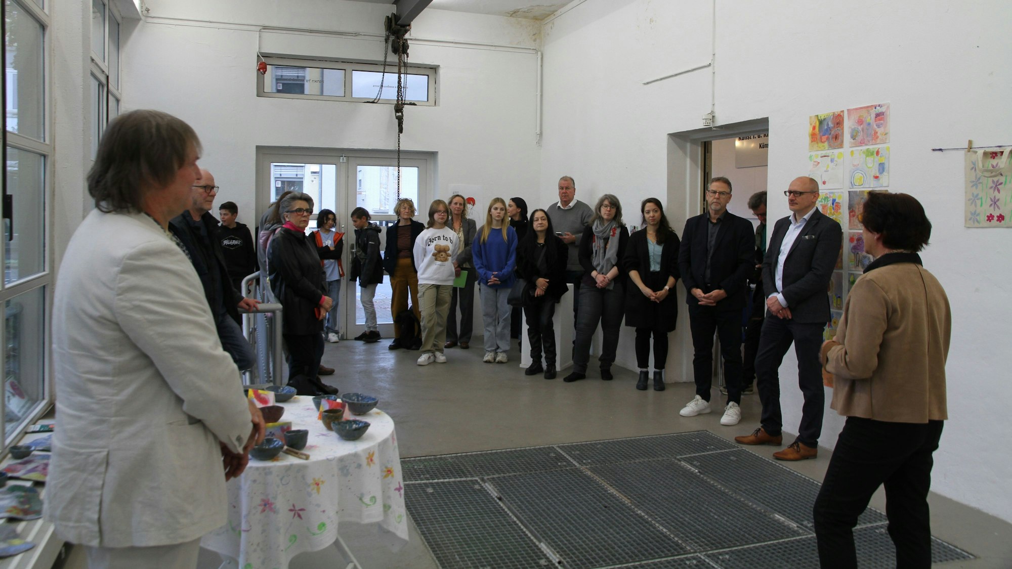 Eine Gruppe von Menschen in einem hellen Ausstellungsraum mit Bildern und Plastiken