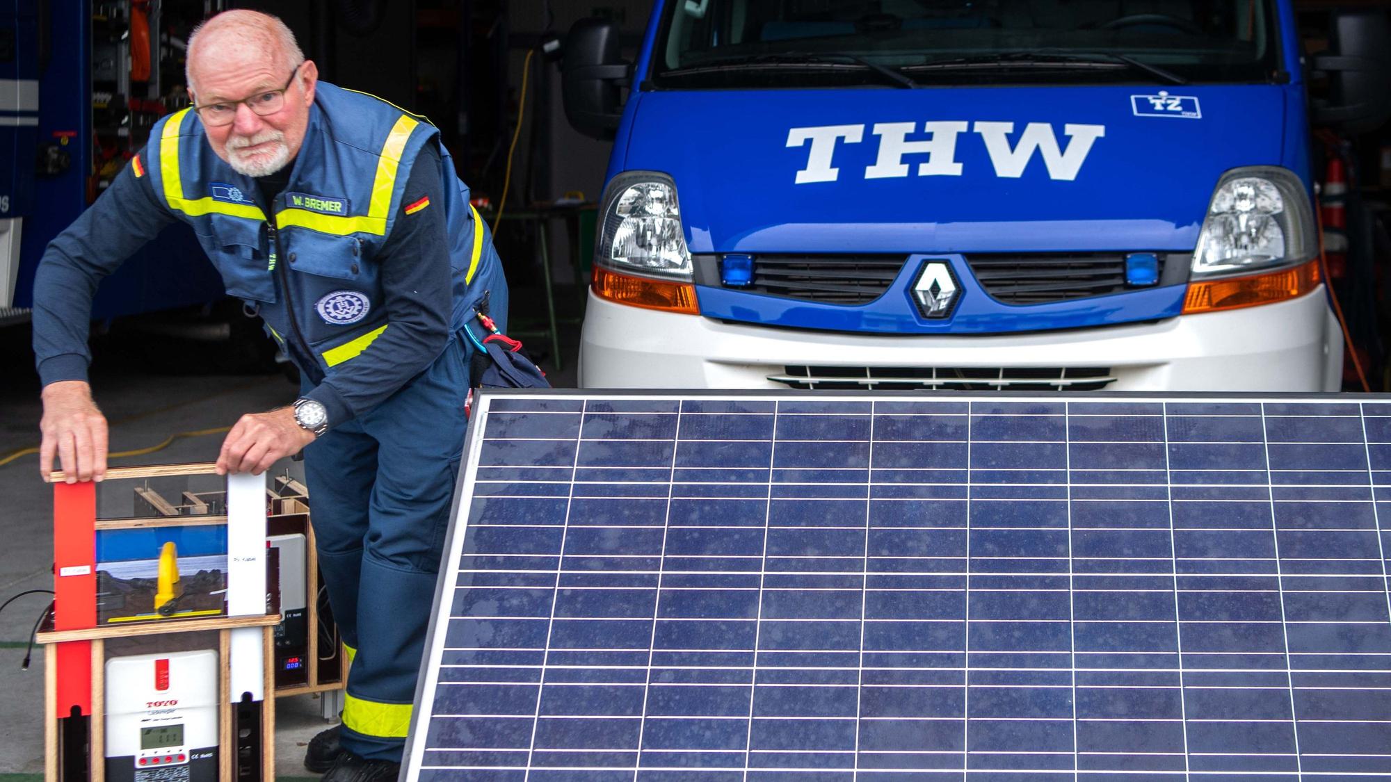 Das Bild zeigt den Entwickler neben einer mobilen Solarfläche. Zudem bedient er die Ladestation.