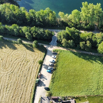 Eine Luftaufnahme zeigt eine Wiese, angrenzende Bäume und den Rand eines Sees.