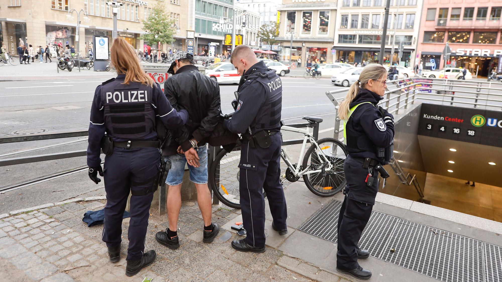 Polizisten und Ordnungsamt kontrollieren am Neumarkt in Köln einen Mann.