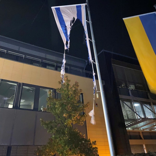 Die Reste einer israelischen Flagge, die an einem Fahnenmast vor dem Rathaus in Mechernich hängt, ist zu großen Teilen verbrannt. Daneben ist eine ukrainische Fahne zu sehen.