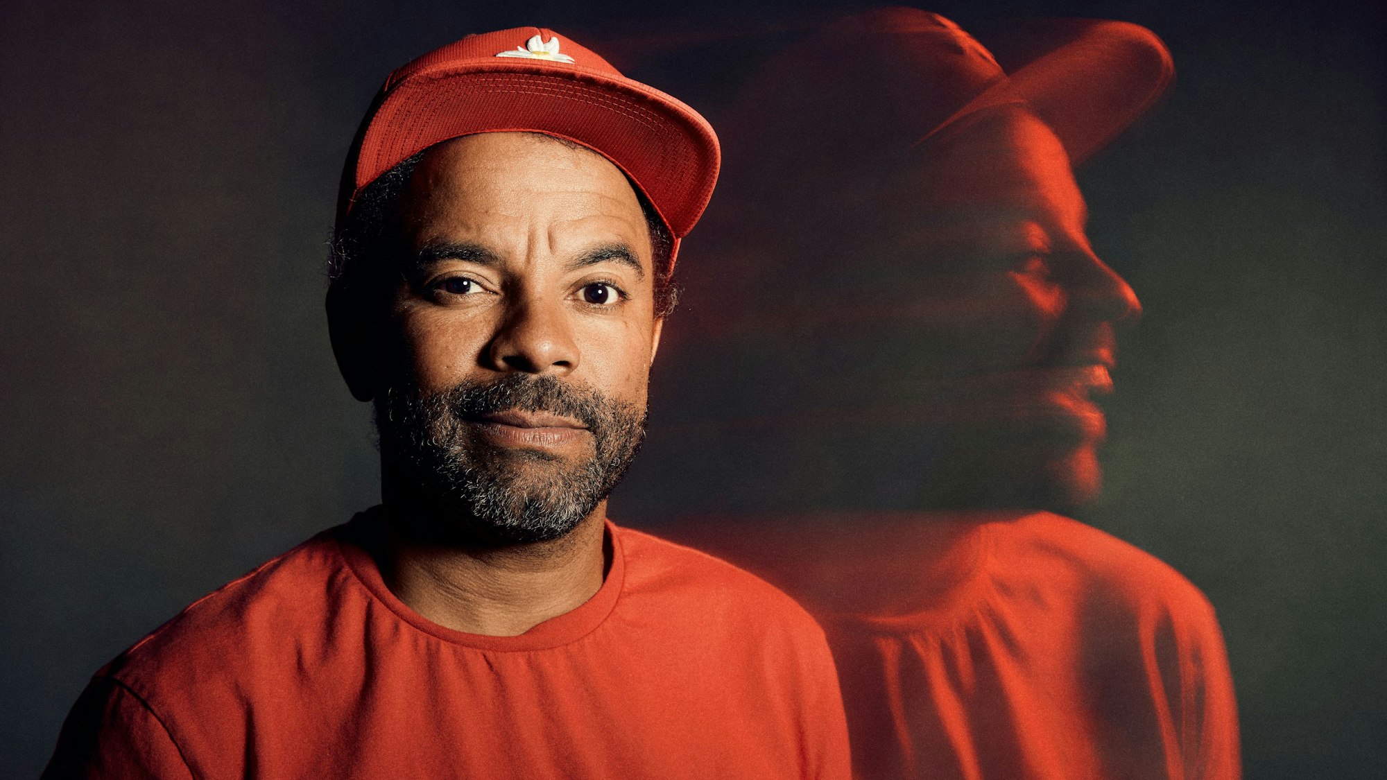 Simon Pearce lächelt in die Kamera, rechts von ihm sieht man ihn nochmal als lachende, verschwommene Silhouette.