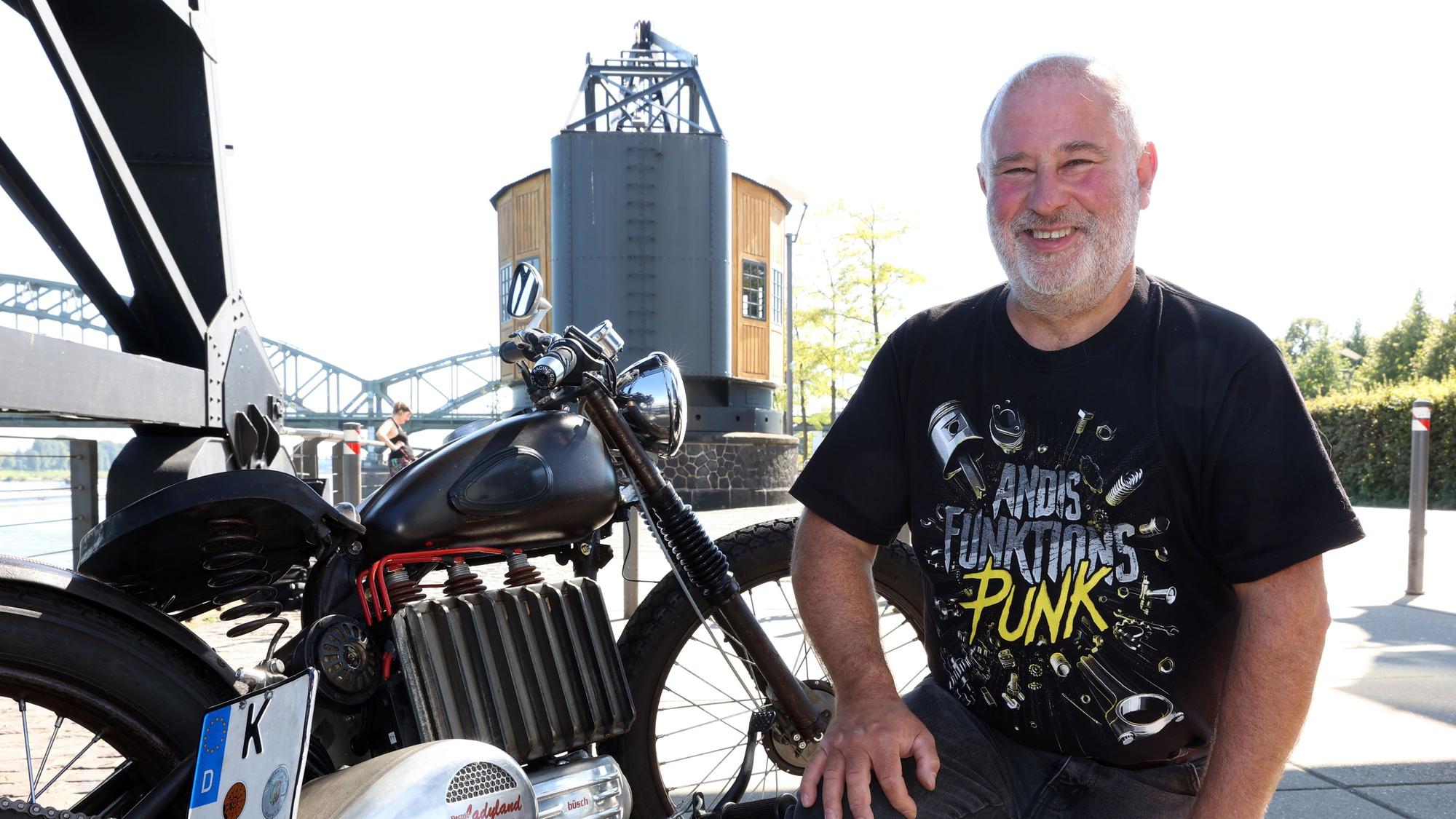 Klaus Mittendorfer kniet neben seinem Motorrad.