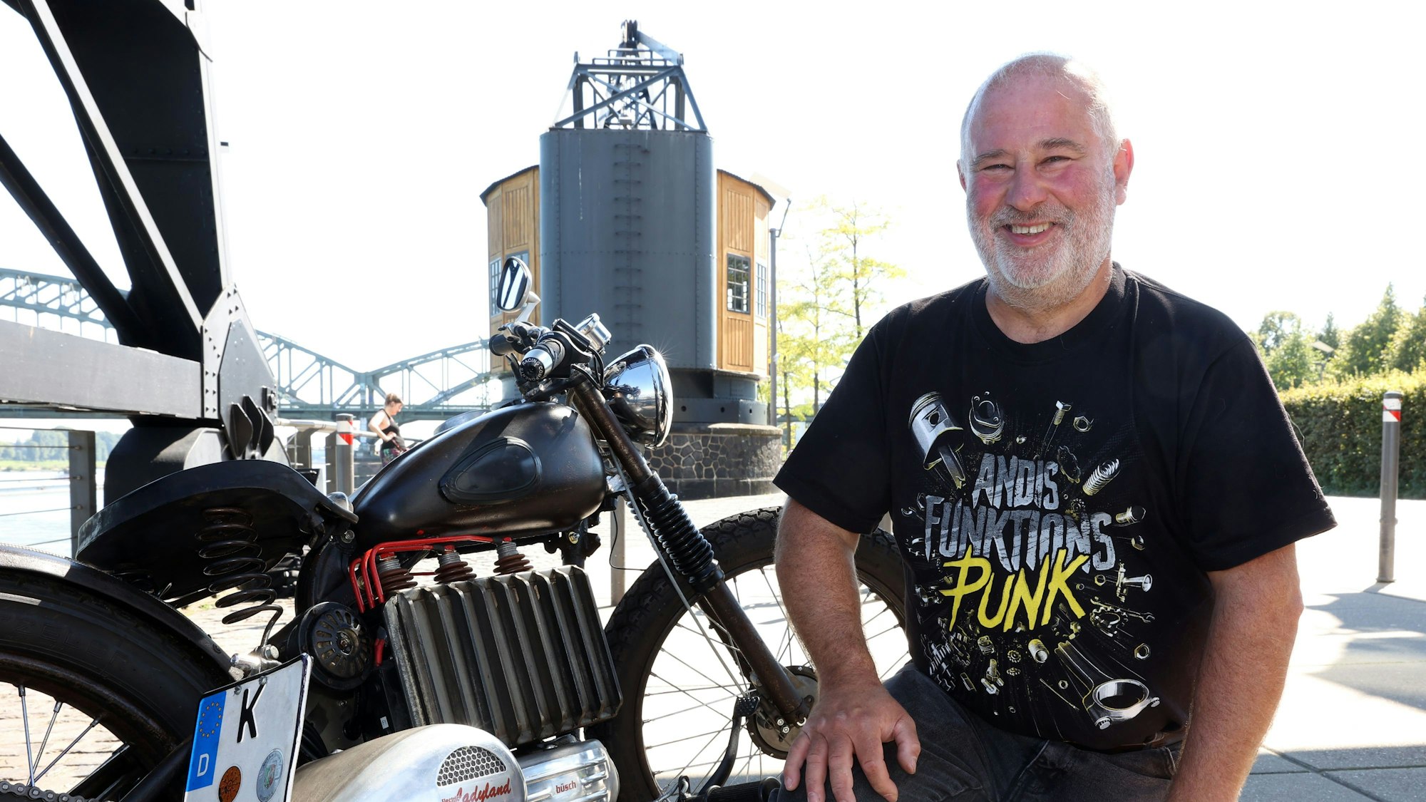 Klaus Mittendorfer kniet neben seinem Motorrad.