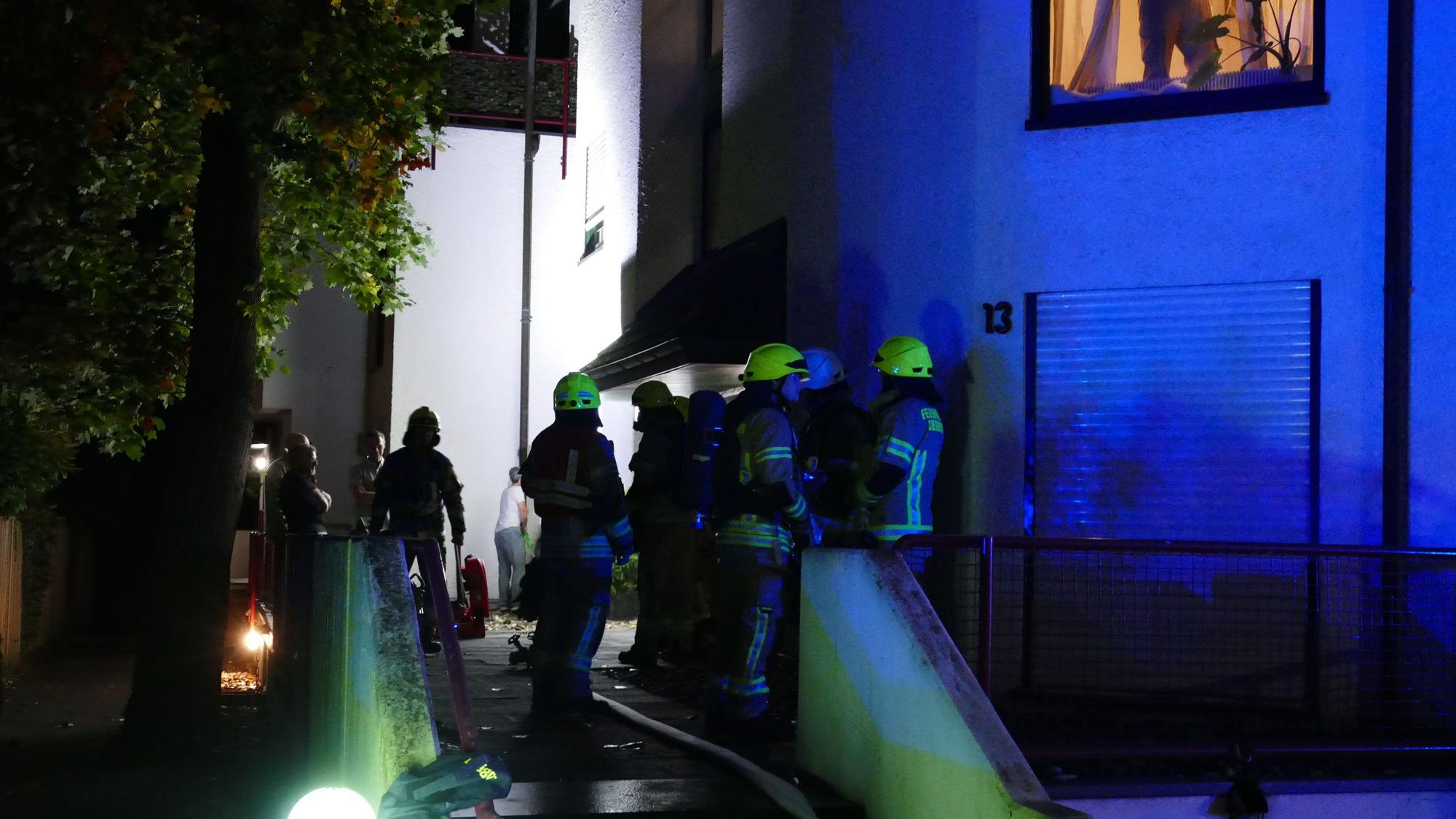 Feuerwehrleute stehen vor einem Wohnhaus.