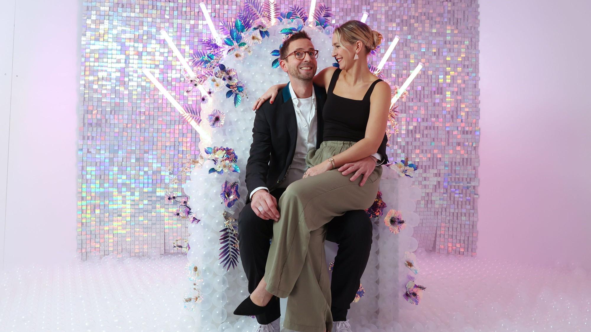 Selina Weiershäuser und Nico Zingelmann sitzen auf einem weißen Stuhl mit Blumen und durchsichtigen Bällen.