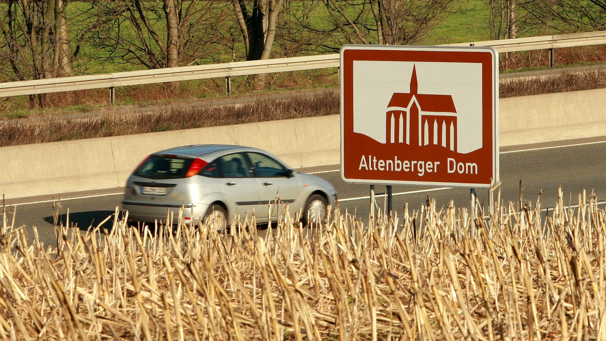 Ein Auto fährt auf der A1 an einem touristischen Hinweisschild für den Altenberger Dom vorbei,