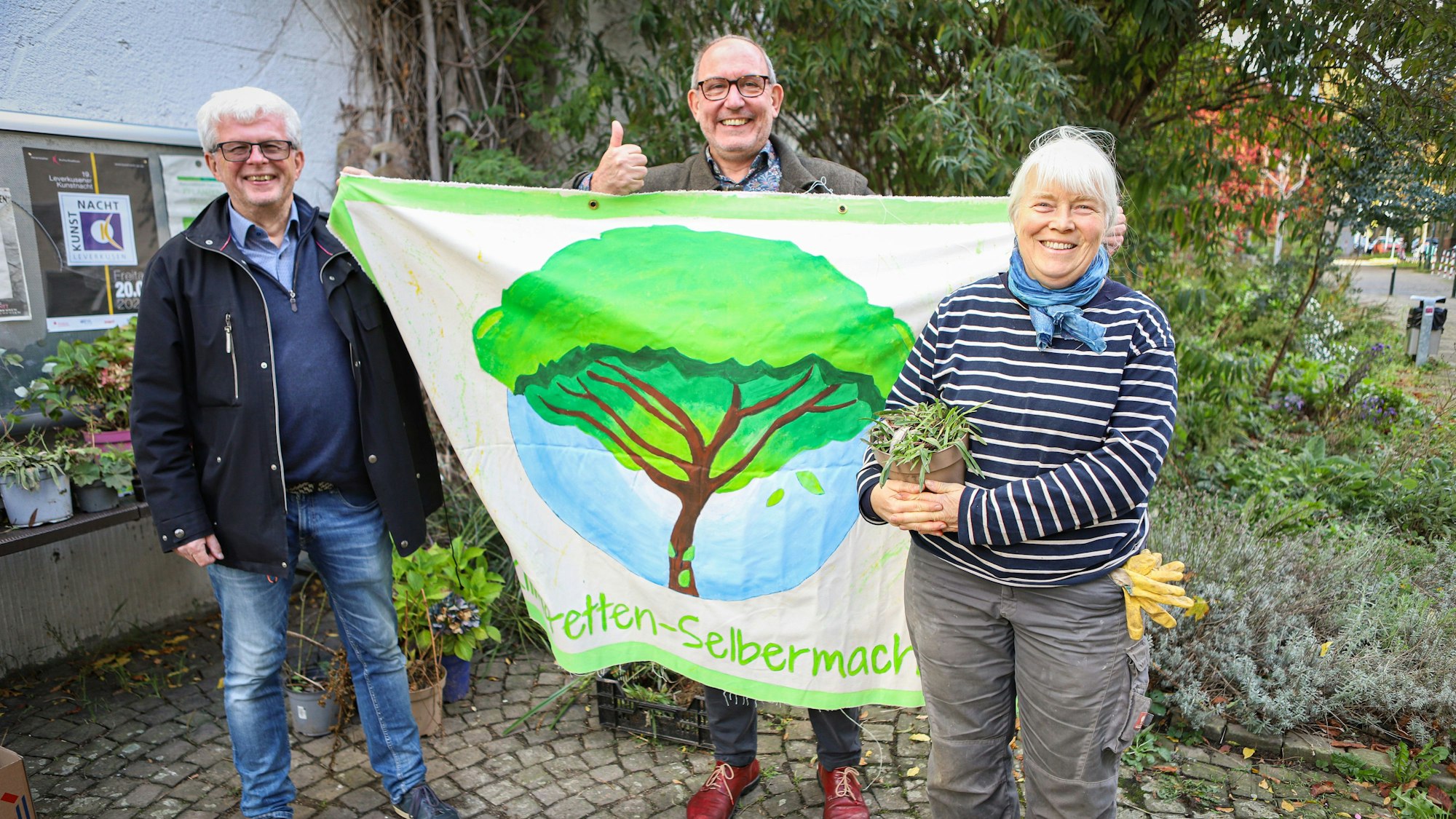 Drei Menschen mit Pflanzen und Plakat