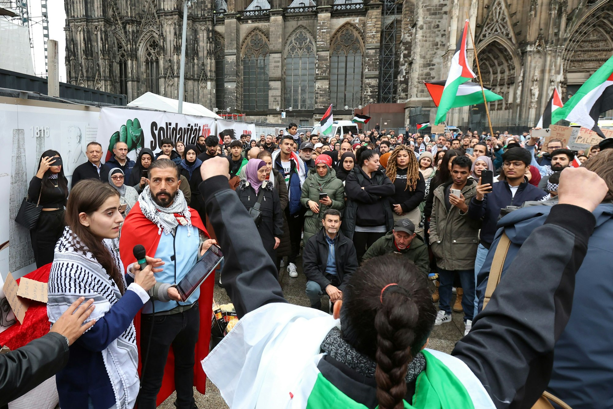 Ein junges Mädchen mit Palästinensertuch spricht auf der Demo in ein Mikrofon.