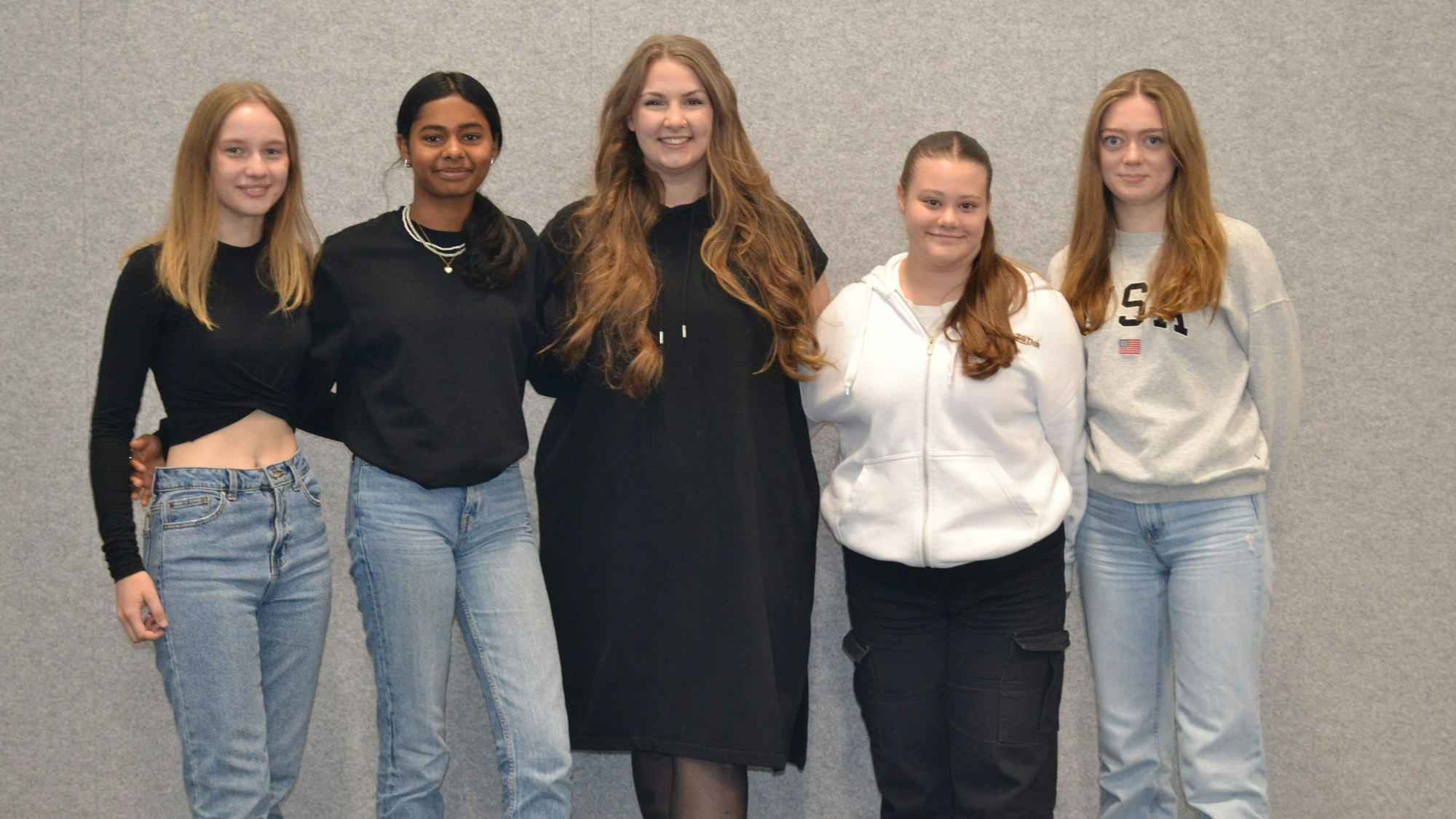 Fünf junge Frauen vor einer hellgrauen Wand.