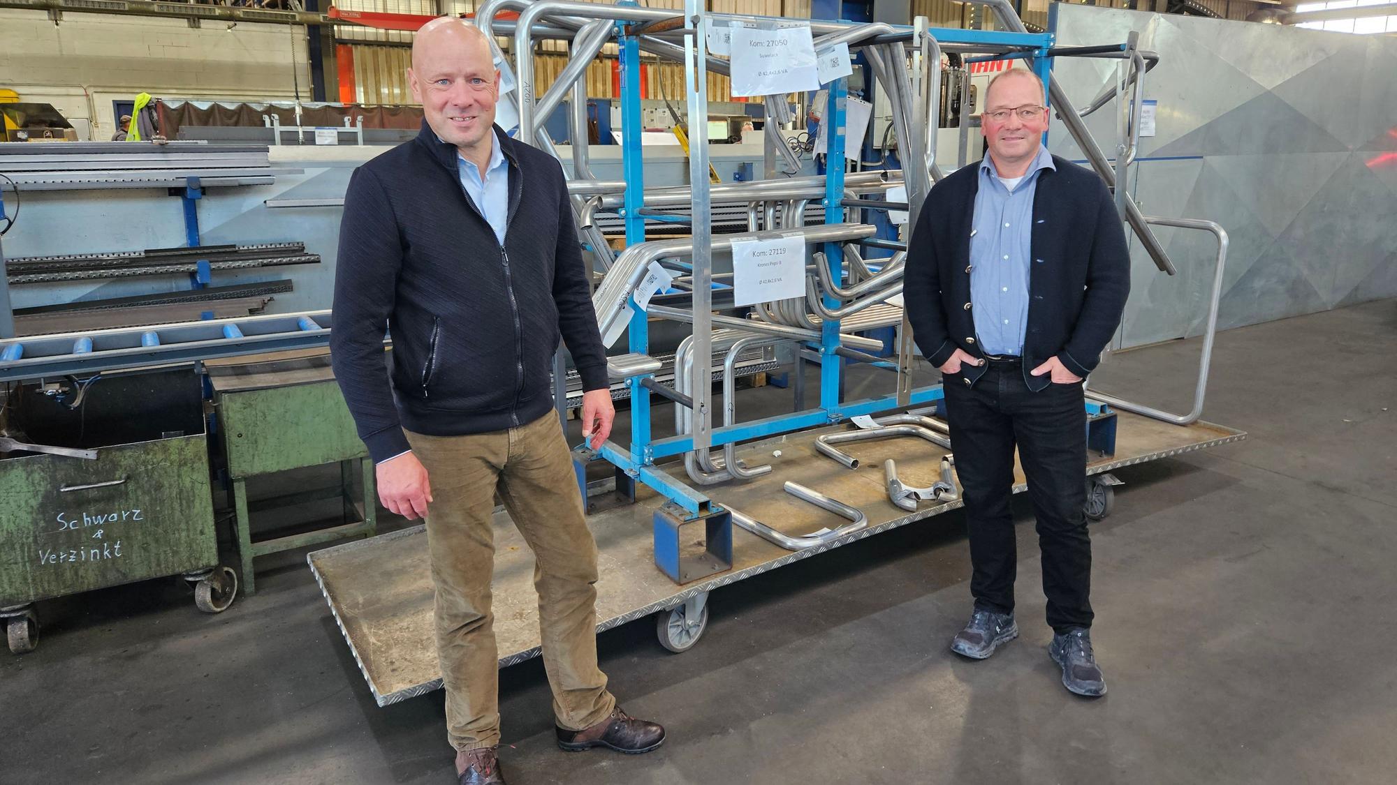 Thomas und Josef Müller (r.) stehen vor Stahlbauteilen in einer Werkshalle.