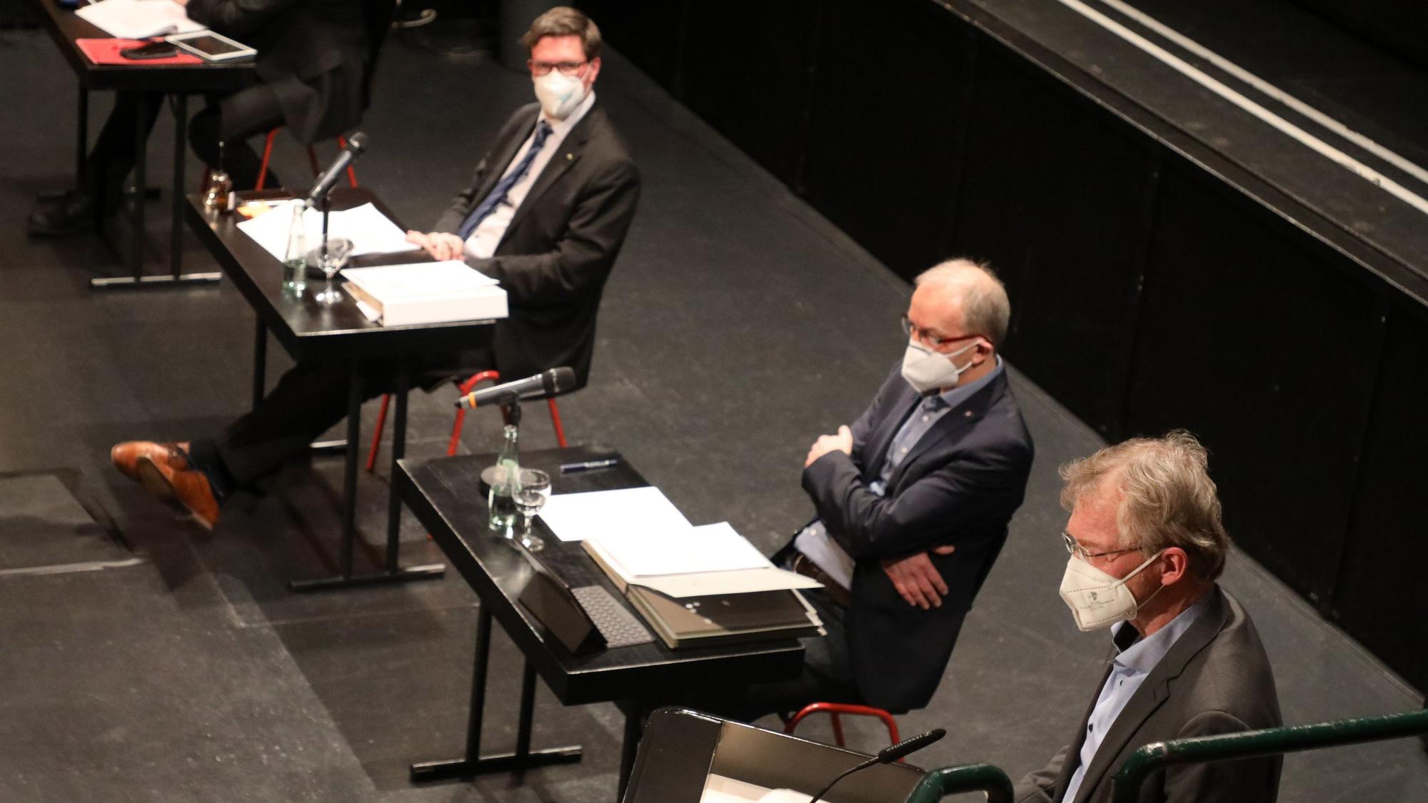 Drei Männer sitzen mit FFP2-Masken an Tischen in einer Sitzung des Kreisausschuss des Rheinisch-Bergischen Kreises.
