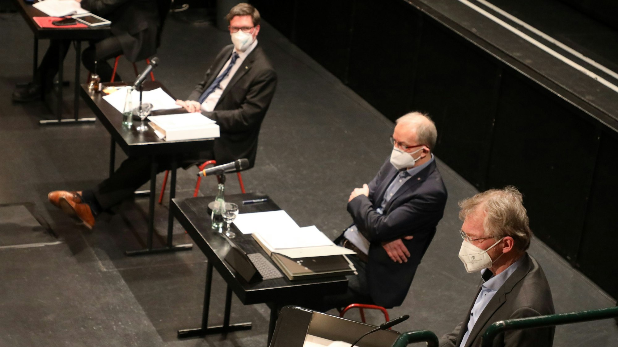 Drei Männer sitzen mit FFP2-Masken an Tischen in einer Sitzung des Kreisausschuss des Rheinisch-Bergischen Kreises.