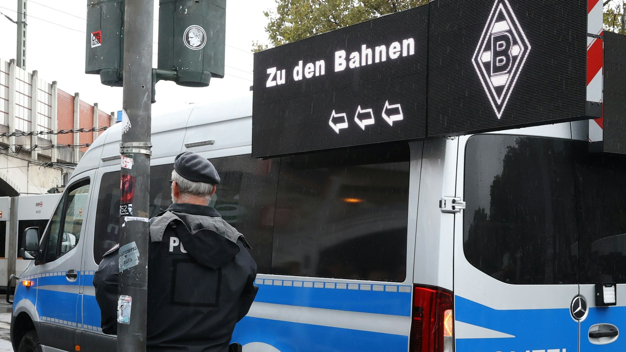 Ein Polizist steht vor einem Polizeiwagen.