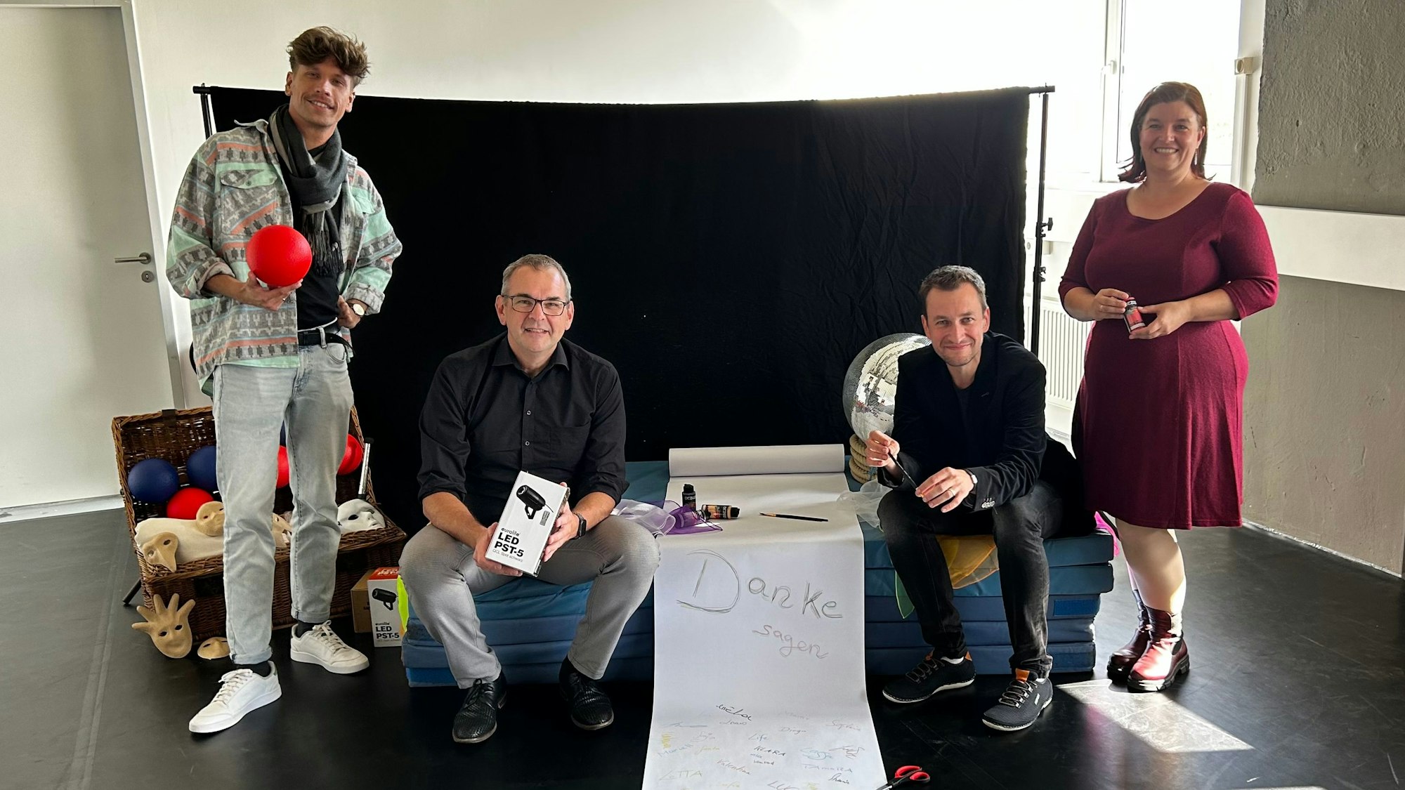 Drei Männer und eine Frau mit einem Transparent, auf dem groß das Wort Danke steht