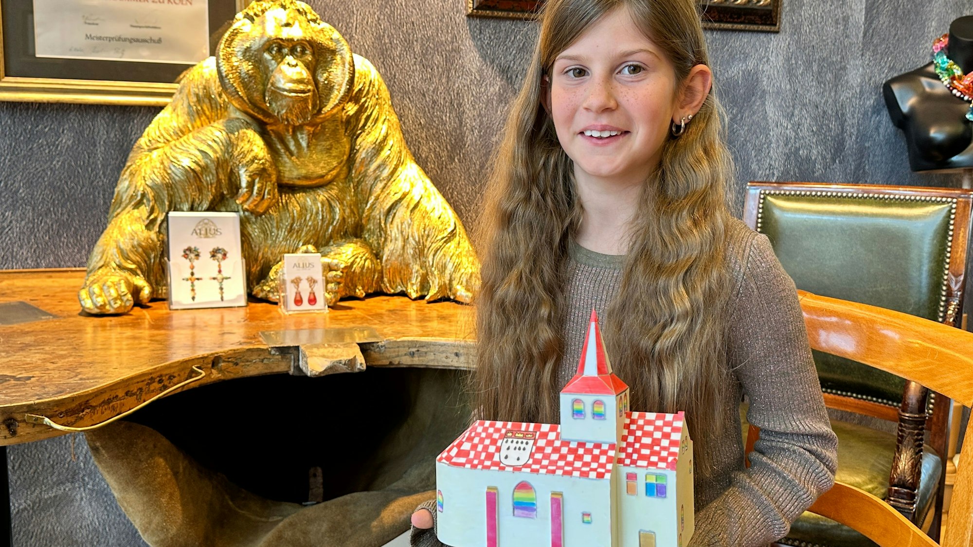 Ein junges Mädchen sitzt auf einem Stuhl und hält einen Preis in der Hand.