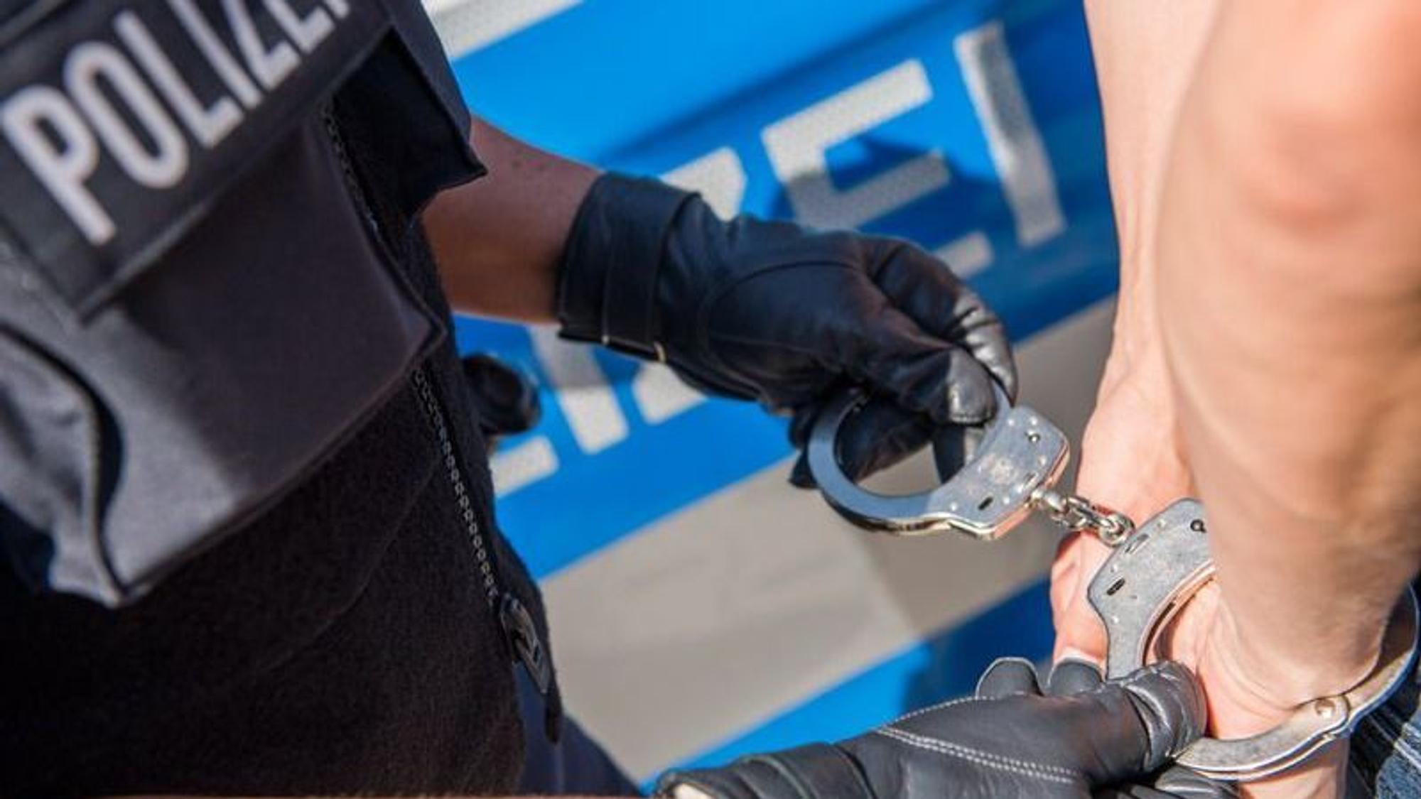 Die Polizei nimmt eine Person mit Handschellen fest.