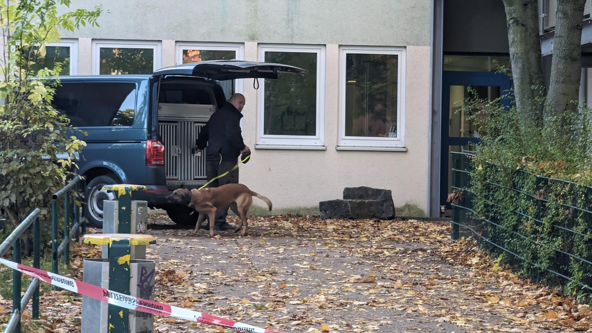Ein Polizist steht mit einem Spürhund vor einem Schulgebäude in Erfurt. Nach einer Bombendrohung ist eine Schule in Erfurt evakuiert worden.