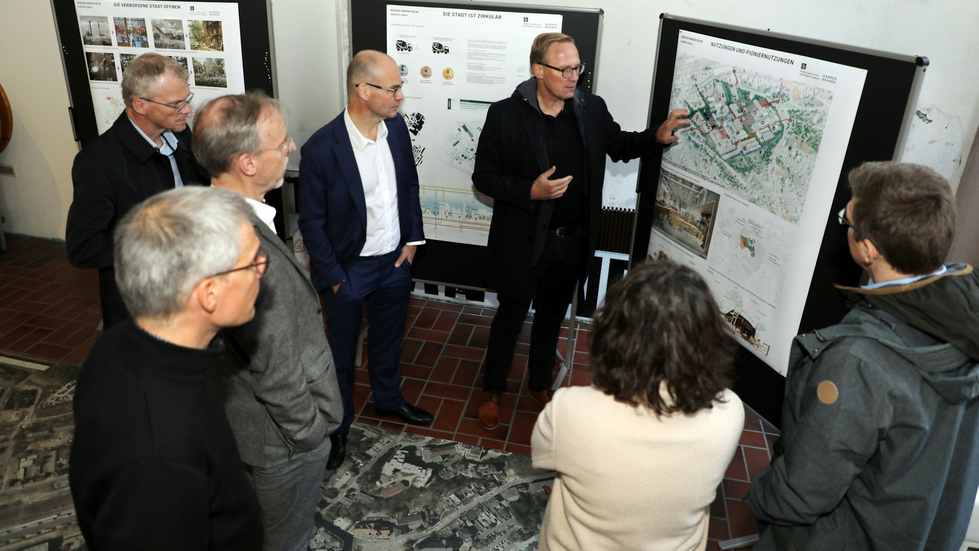 Die Beteiligten stehen vor Bauplänen.