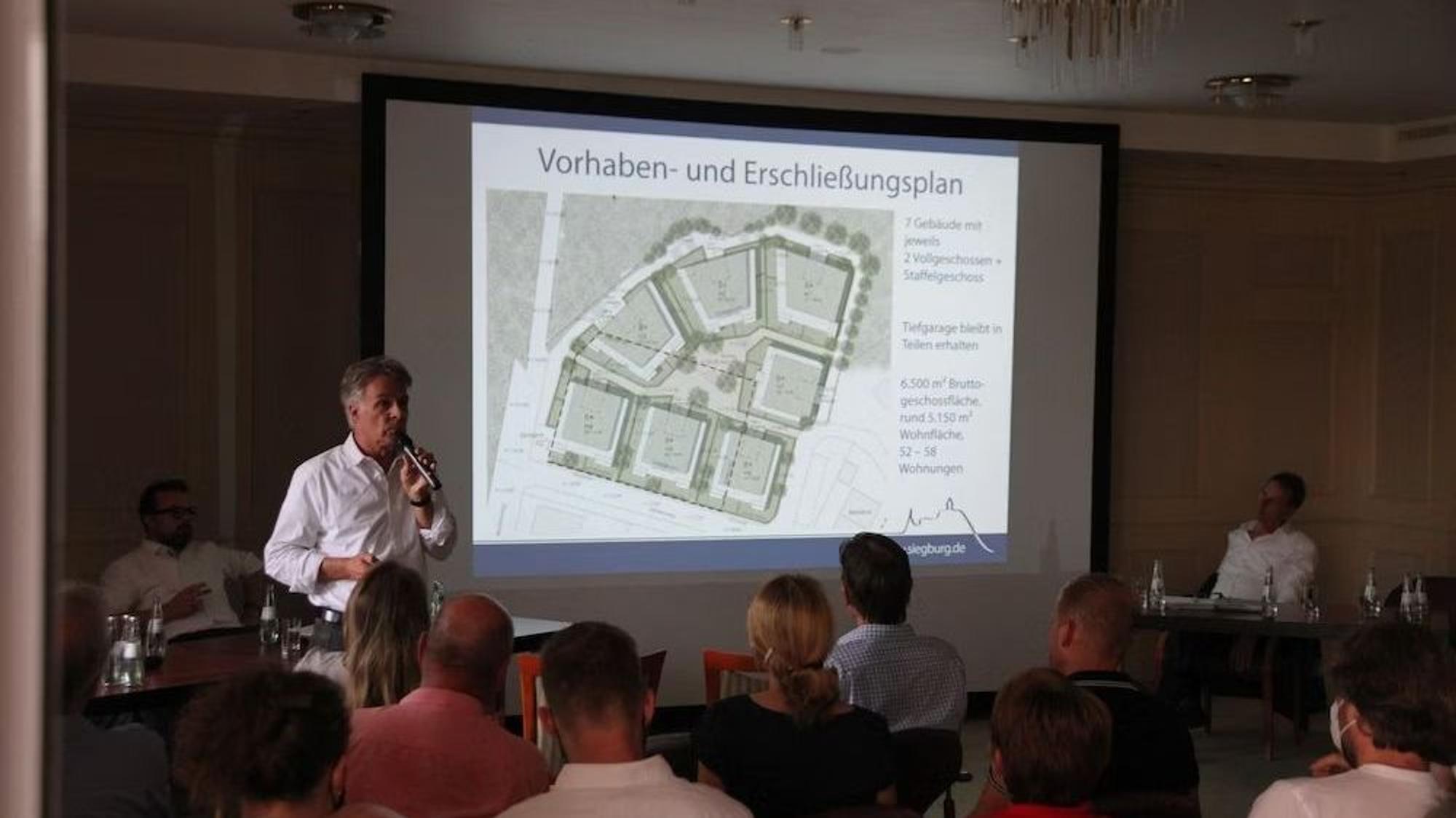 Ein Mann erläutert vor einer Leinwand eine Architekturplanung