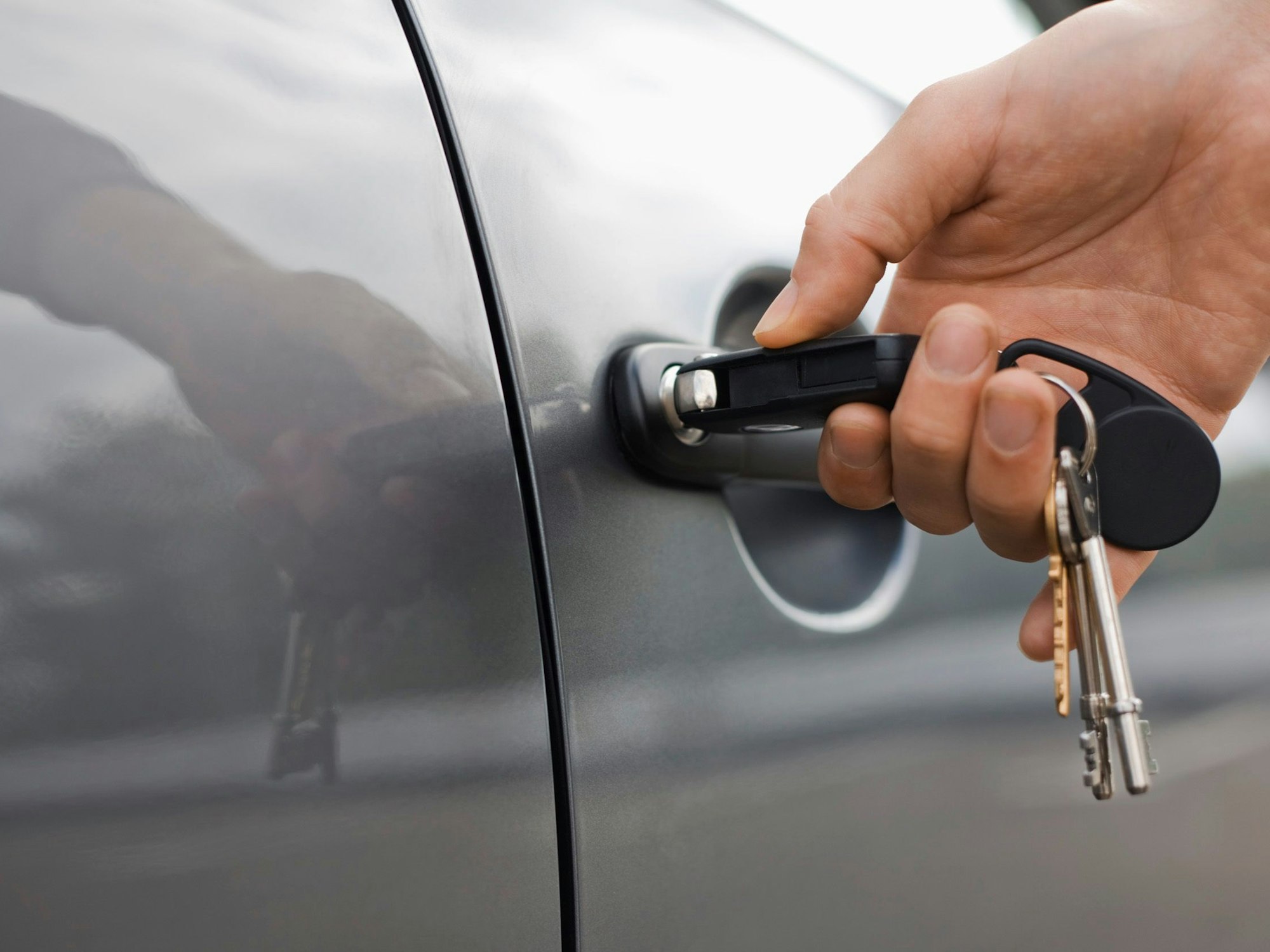 Das Bild zeigt, wie eine Person einen Autoschlüssel in das Türschloss steckt.