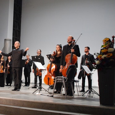 Das Folkwang Kammerorchester Essen unter der Leitung des Dirigenten Johannes Klumpp eröffnet die Spielzeit der Wallgrabenkonzerte. Die Musiker stehen auf der Bühne und halten ihre Instrumente in den Händen.