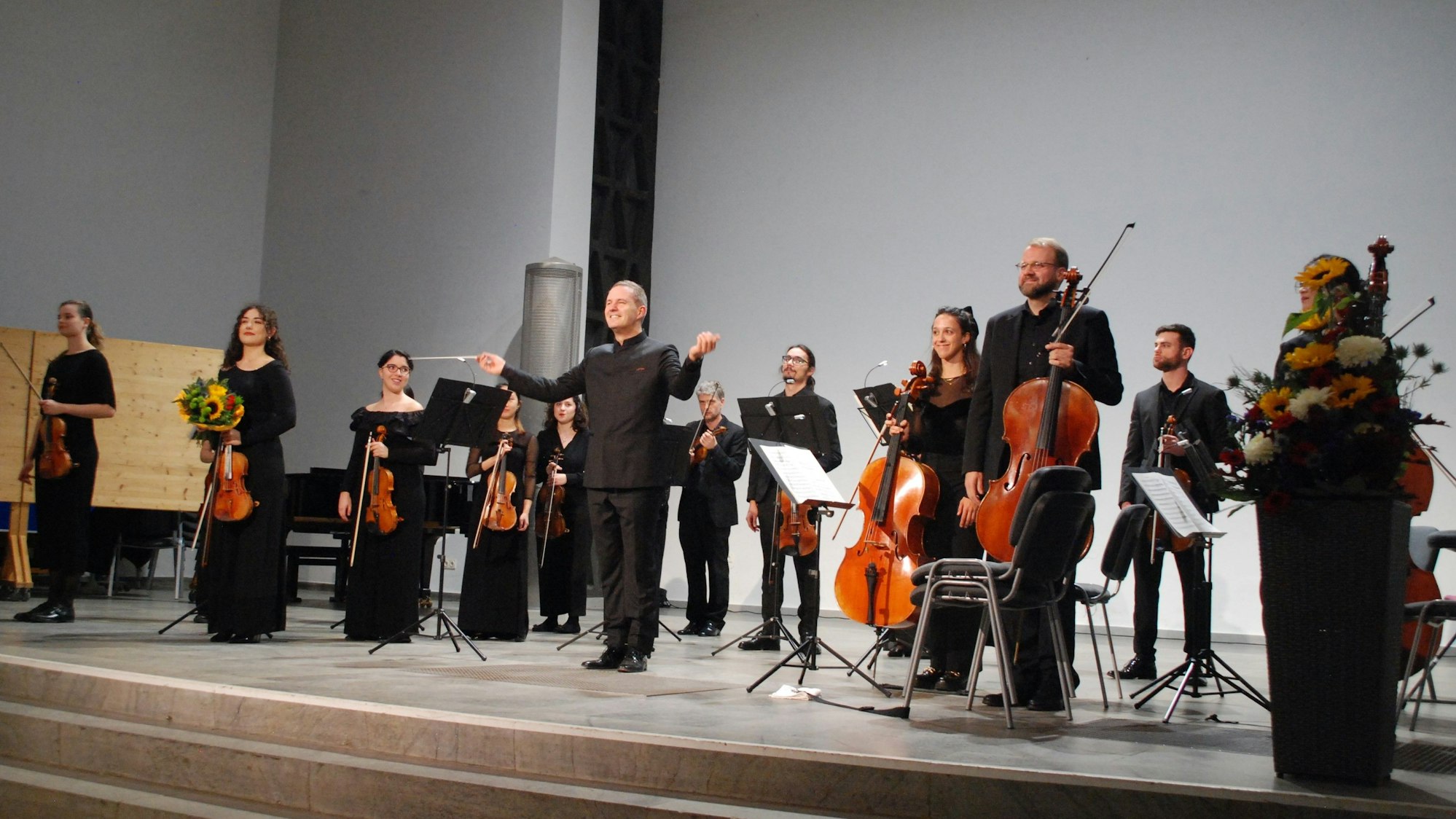 Das Folkwang Kammerorchester Essen unter der Leitung des Dirigenten Johannes Klumpp eröffnet die Spielzeit der Wallgrabenkonzerte. Die Musiker stehen auf der Bühne und halten ihre Instrumente in den Händen.