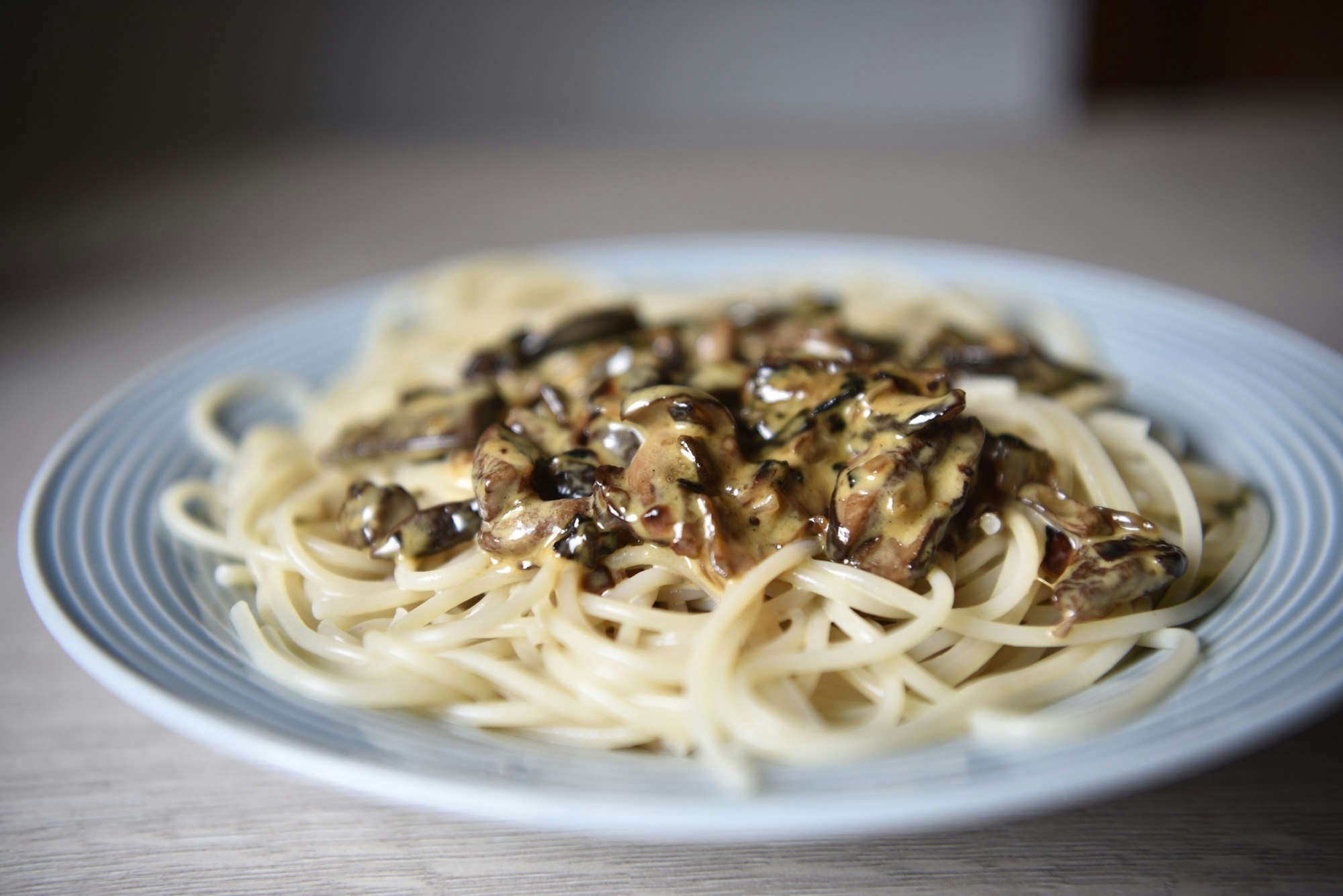 Auf einem blauen Teller liegen Spaghetti in einer Pilz-Sahne-Sauce.