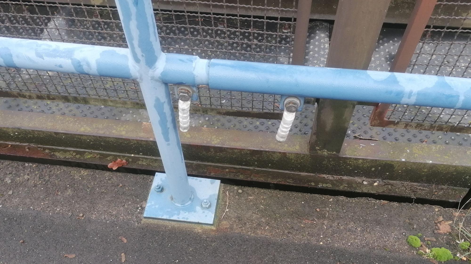 Fehlende Erdungskabel an einem Geländer der Bahnstation.
