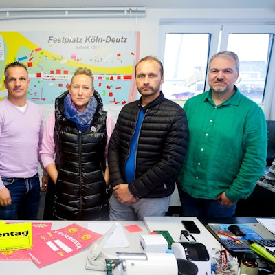 Fünf Menschen stehen nebeneinander in einem Raum.