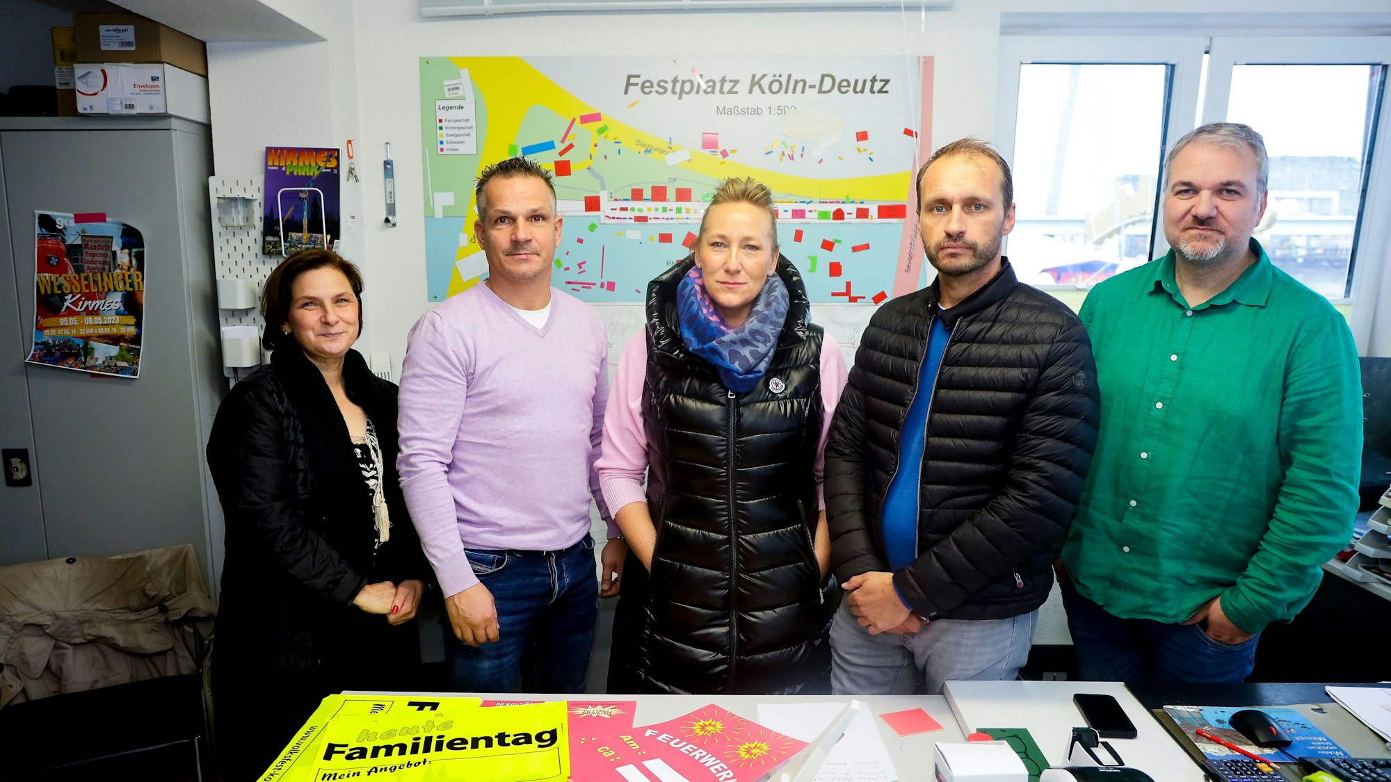 Fünf Menschen stehen nebeneinander in einem Raum.