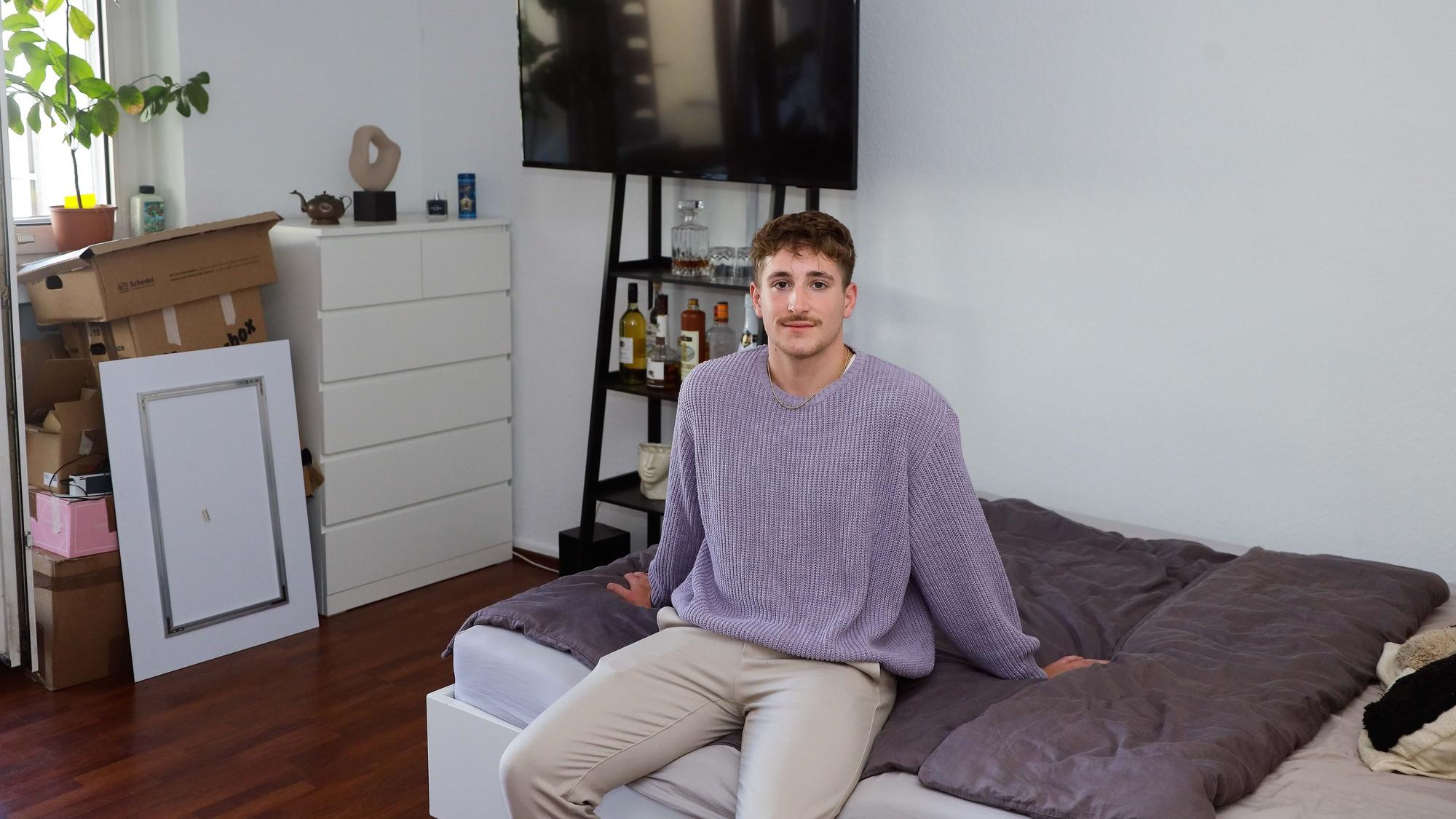 Student Leon sitzt in seinem Kölner WG-Zimmer auf dem Bett.