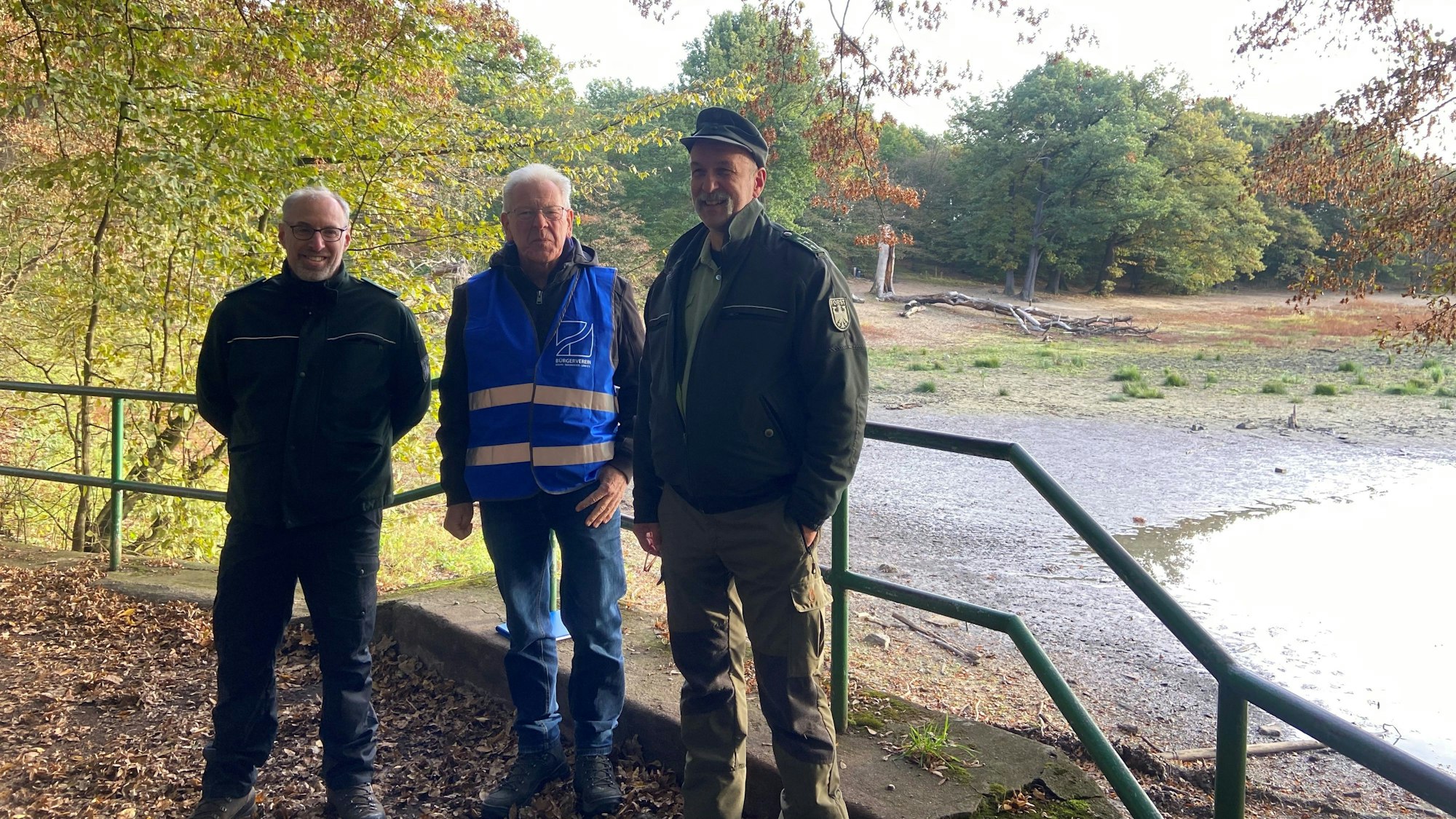 Drei Männer stehen vor dem Teich.