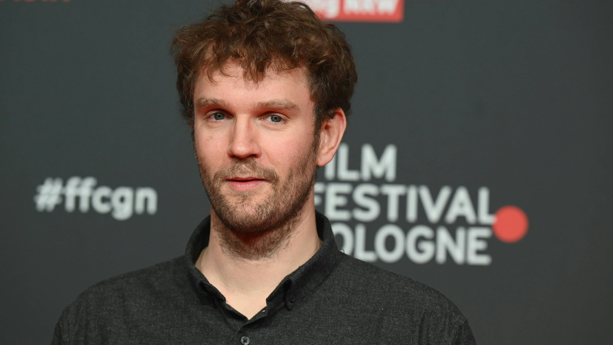 Kröger trägt ein schwarzes Hemd. Im Hintergrund die Aufschrift: Film Festival Cologne.
