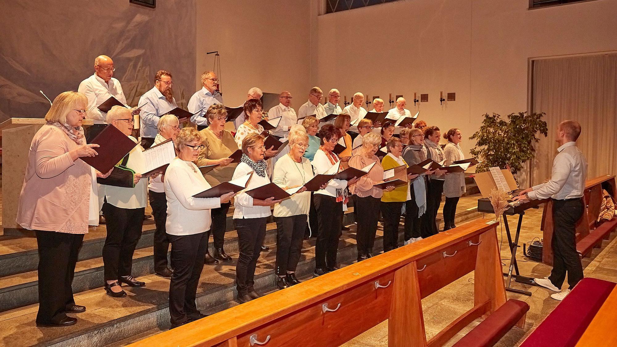 Der Hellenthaler Kirchenchor singt im Altarraum der Kirche. Rechts am Keyboard musiziert Dirigent Christopher Schneider.